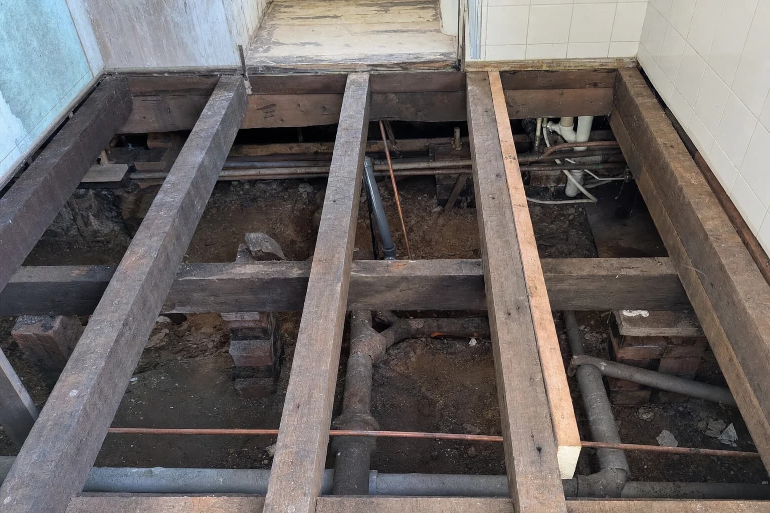 The opened floor of a Bangalow cottage bathroom showing hardwood bearers and joists below