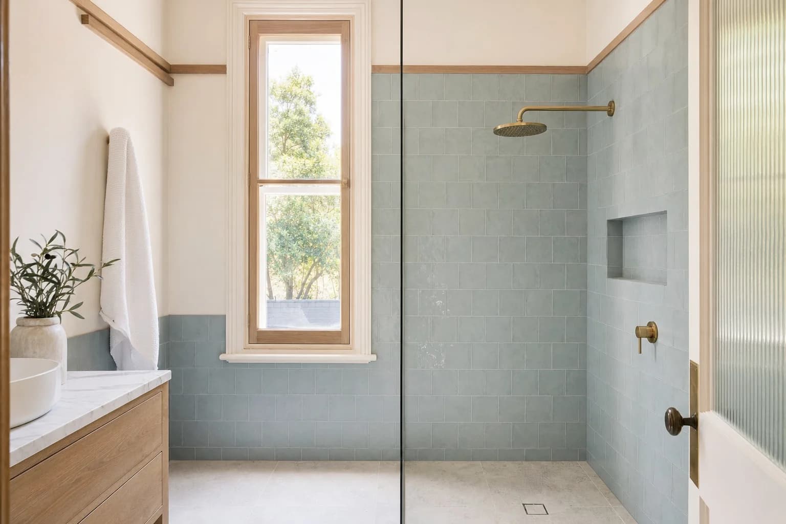 A level entry walk in shower with sea blue tile and brushed brass taps in a Bangalow cottage