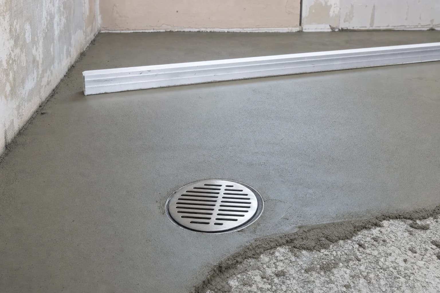 A mortar bed being shaped to slope toward the drain