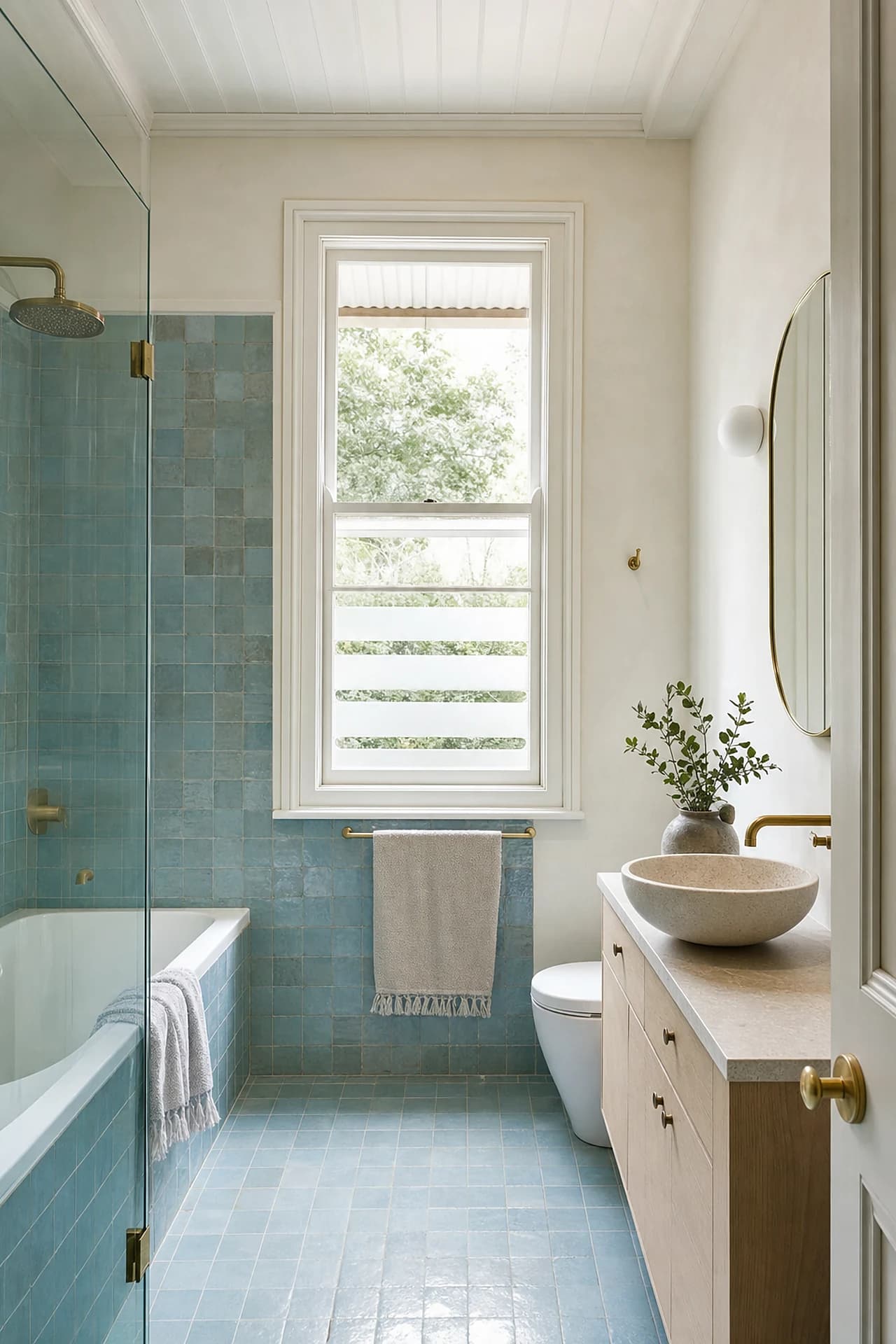A finished bathroom in a Bangalow weatherboard cottage with a tall sash window and sea blue tile
