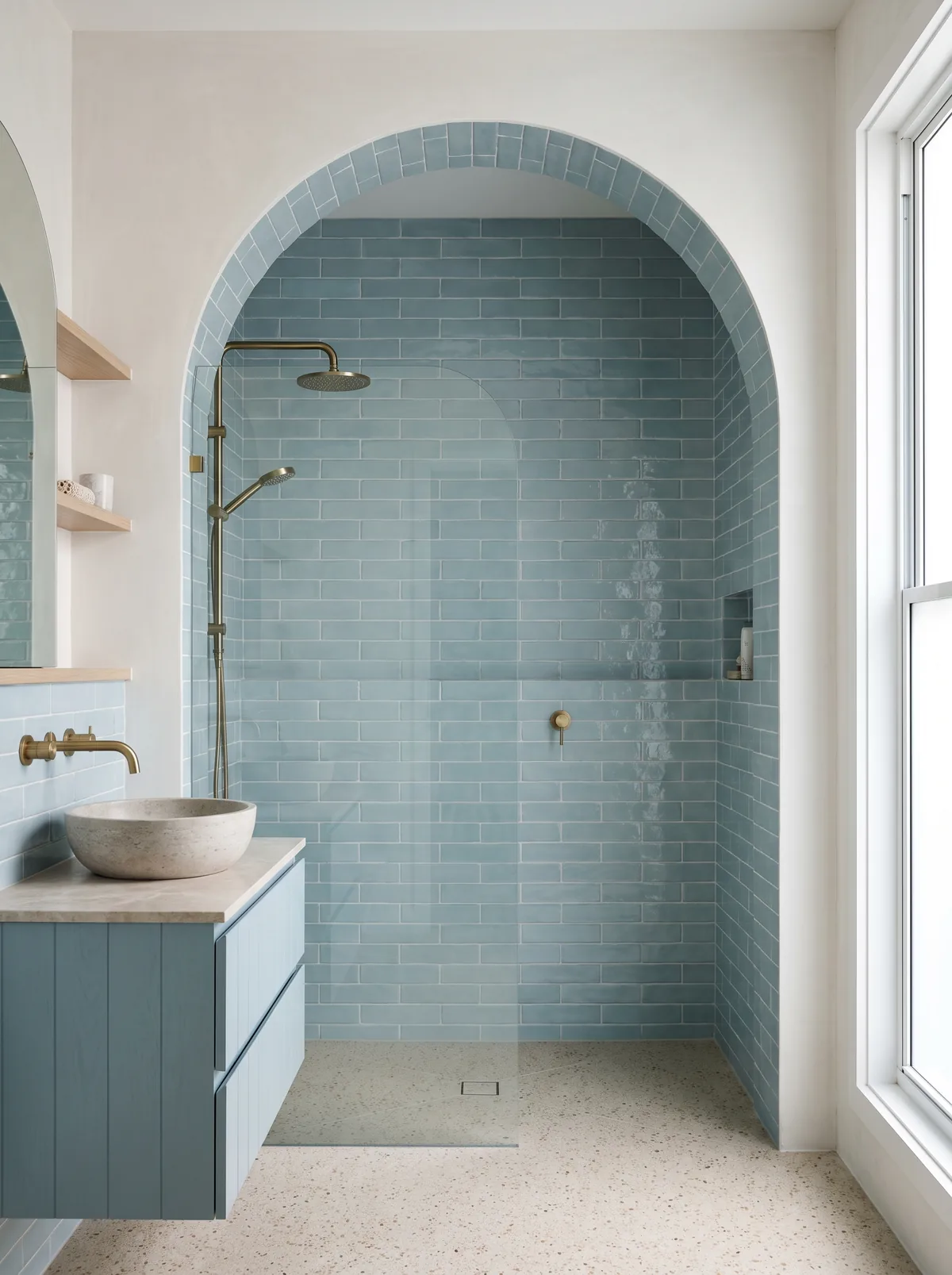A renovated Byron Bay bathroom with an arched shower lined in sea blue handmade tiles