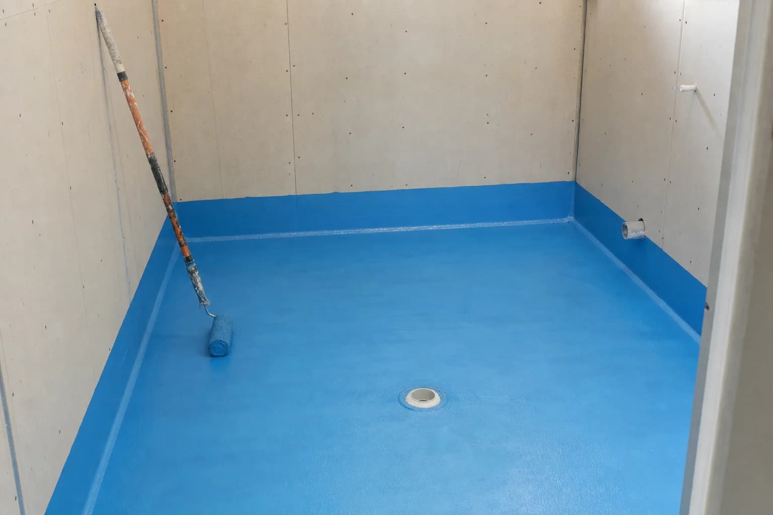 Waterproofing membrane applied across a bathroom floor before tiling