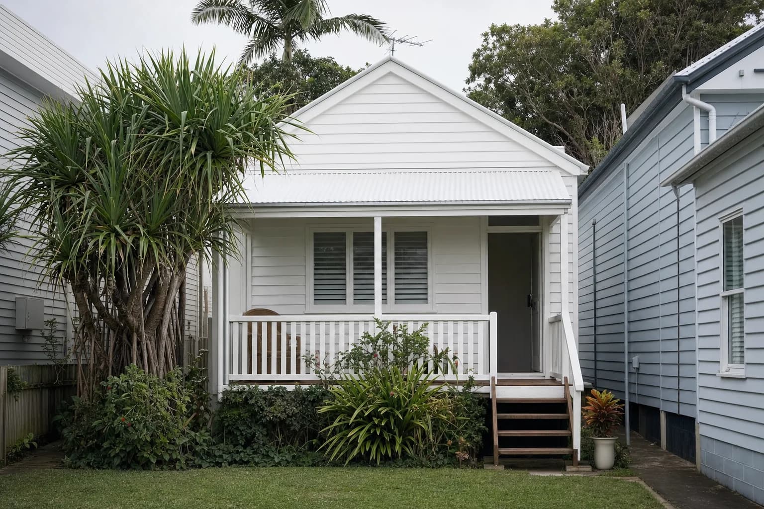 A small white weatherboard cottage on a narrow block in Brunswick Heads