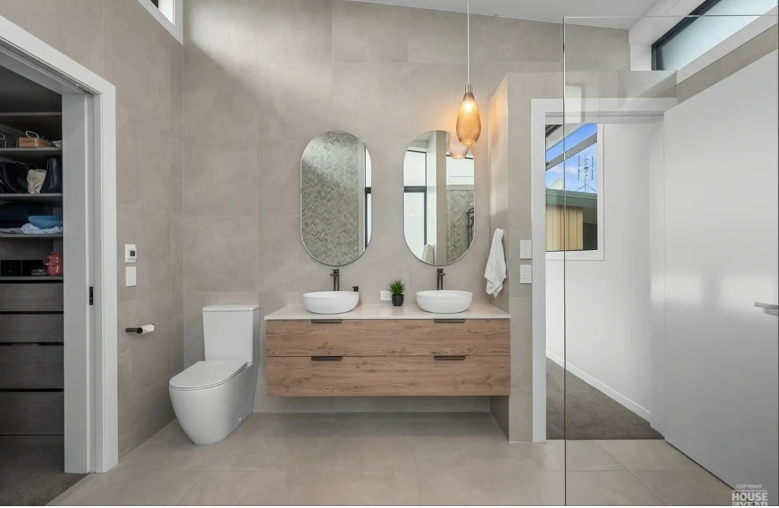 A completed bathroom renovation with twin basins, a pendant light and a walk in shower