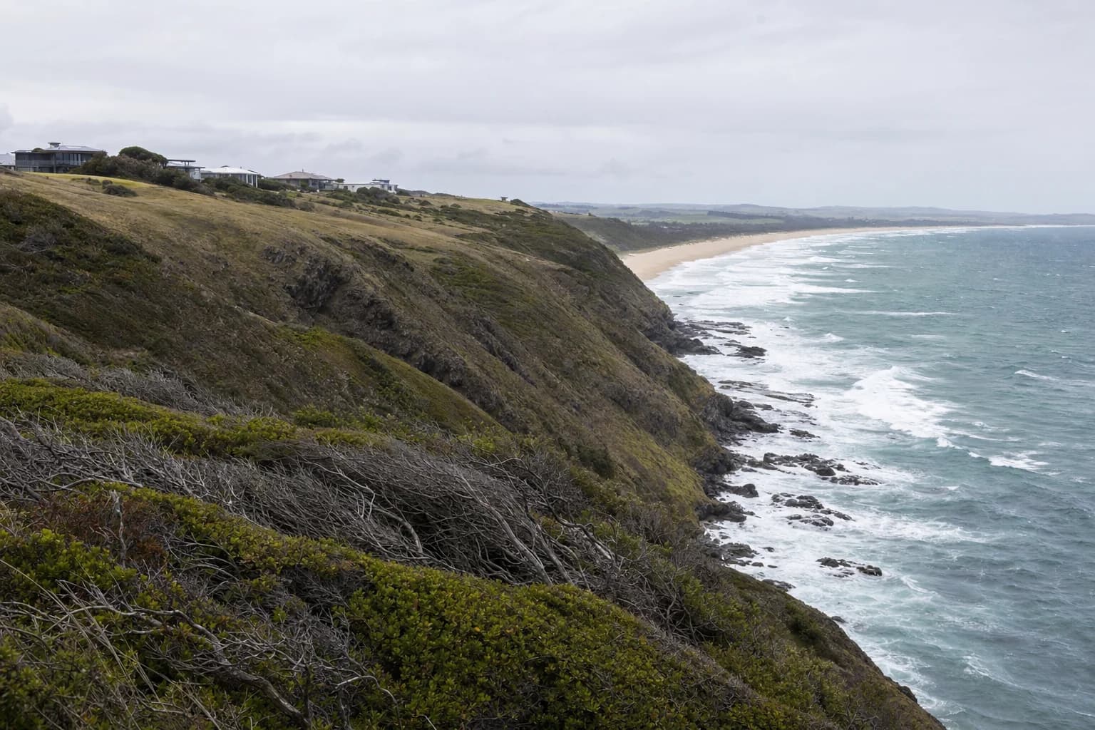 The headland and open coastline at Lennox Head with houses on the rise above the beach